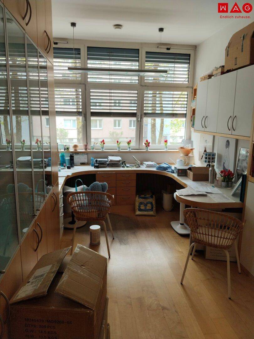 Büroraum mit großem Fenster, Schreibtisch und vielen Schränken, derzeit mit Umzugskartons.