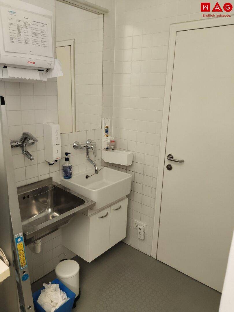 Kleiner Waschraum oder Hauswirtschaftsraum mit zwei Waschbecken, Spiegel und weißen Fliesen.