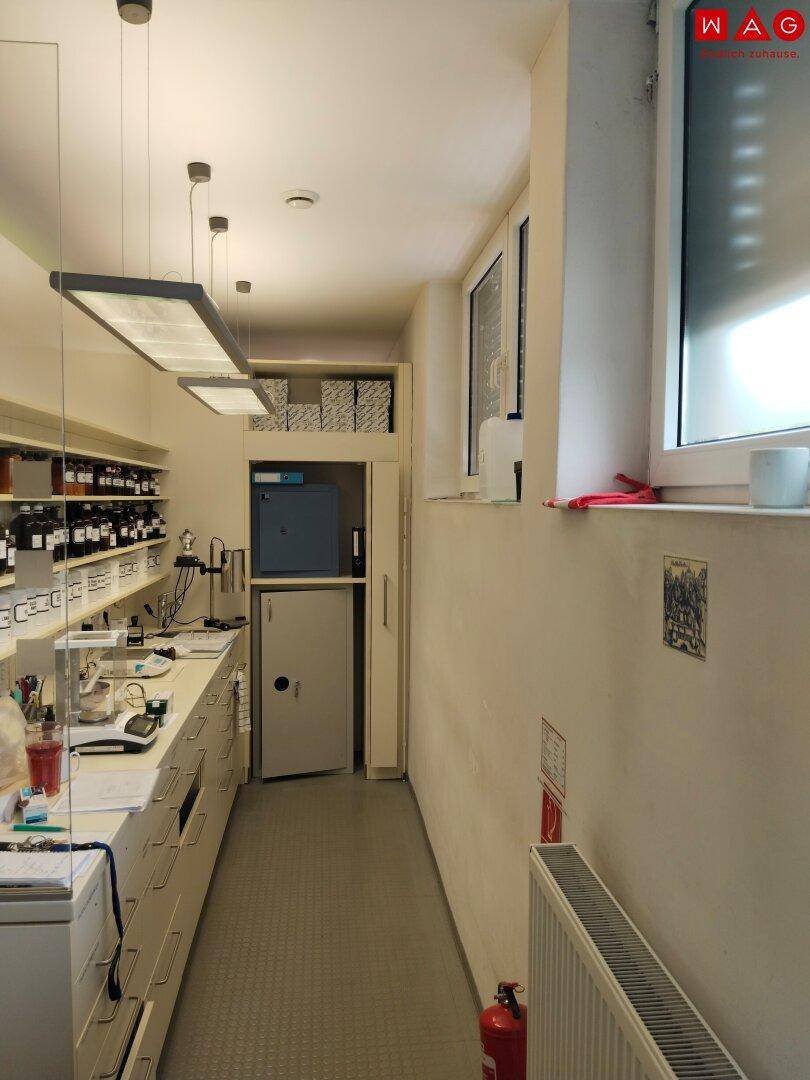 Schmaler Labor- oder Arbeitsbereich mit Regalen, Arbeitsplatte und einem kleinen Fenster.