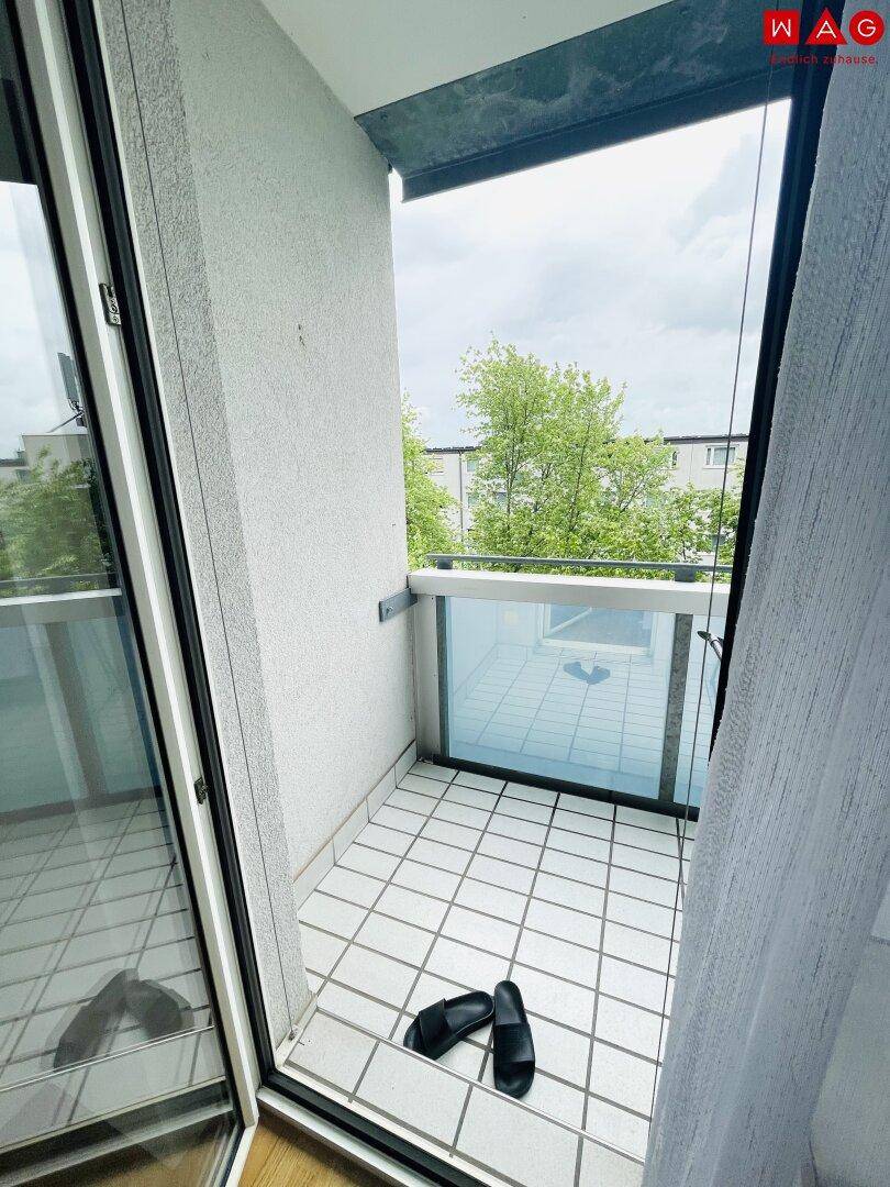 Kleiner Balkon mit Fliesenboden und Glasbrüstung, zugänglich vom Innenraum.