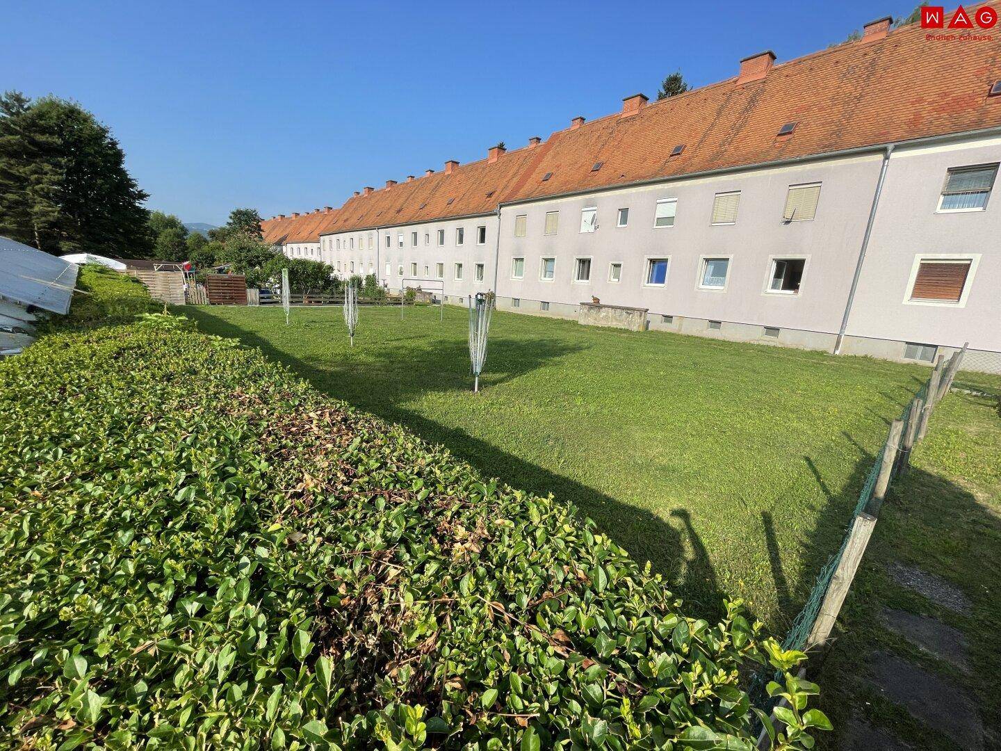 Große, gepflegte Rasenfläche hinter dem Mehrfamilienhaus, ideal zur Erholung.