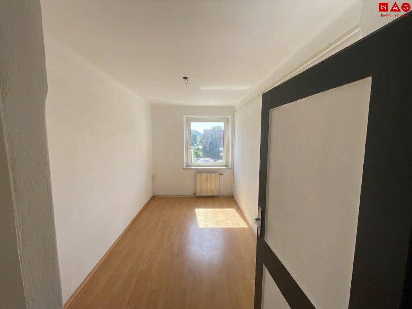 Gemütliches Schlafzimmer mit Laminatboden, einem Fenster und angenehmem Tageslicht.