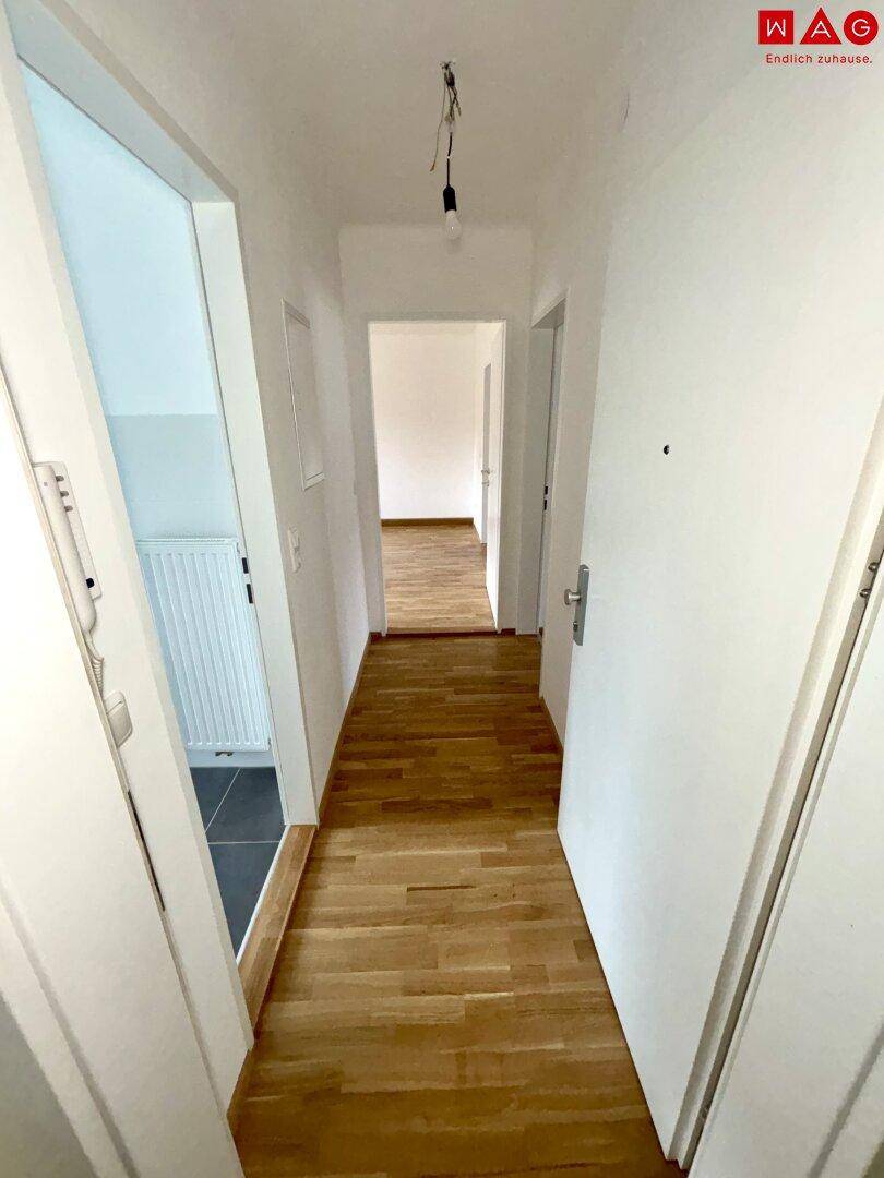 Heller Flur mit Holzparkettboden, der zu weiteren Zimmern der Wohnung führt.