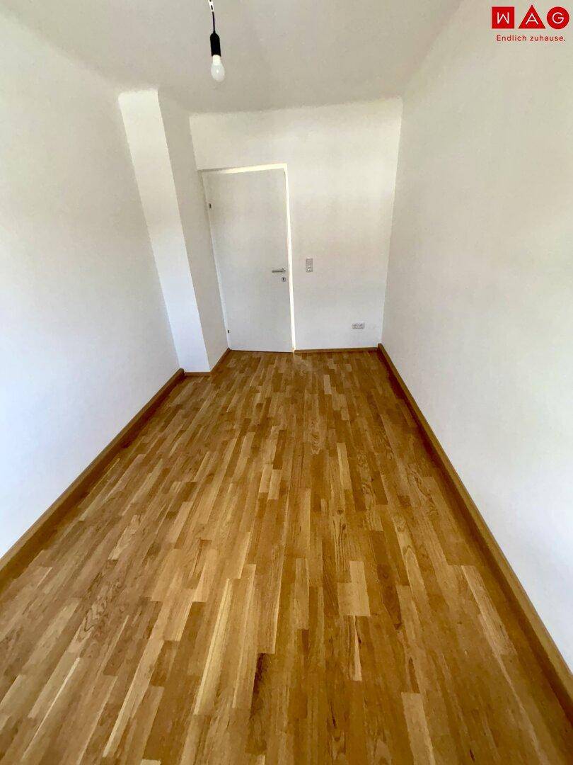 Helles Schlafzimmer mit Parkettboden und weiß gestrichenen Wänden, bereit zur individuellen Gestaltung.