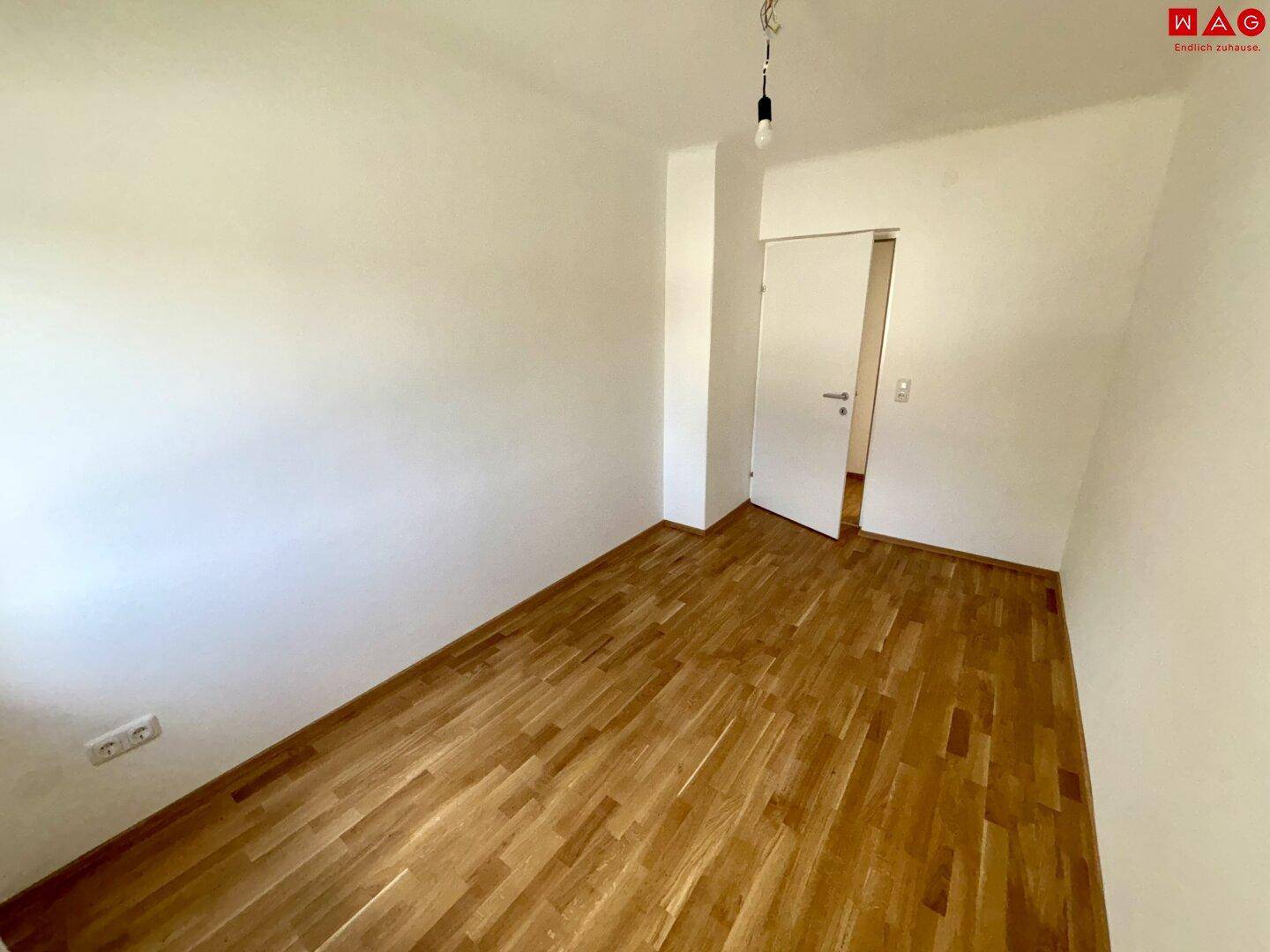 Geräumiges Schlafzimmer mit Parkettboden und weiß gestrichenen Wänden, ideal für Ruhe.