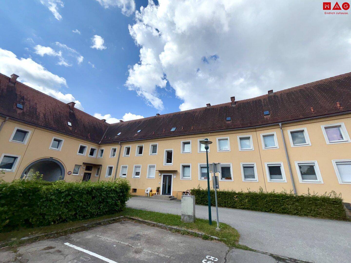 Fassade eines gelben Wohngebäudes mit vielen Fenstern und einem kleinen Eingangsbereich.