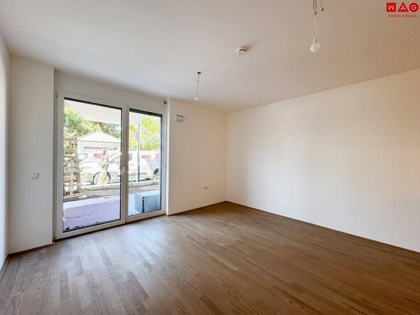 Geräumiger, heller Raum mit Holzboden und großen Schiebetüren, die viel Tageslicht hereinlassen.