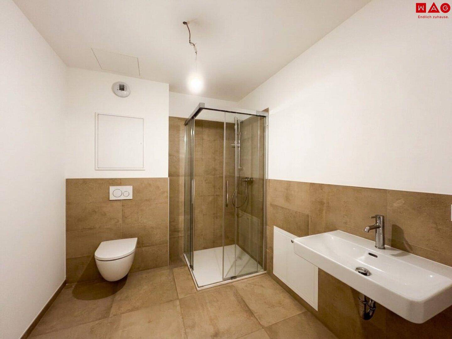 Modernes Badezimmer mit braunen Fliesen, wandhängendem WC, Glasdusche und Einzelwaschbecken.