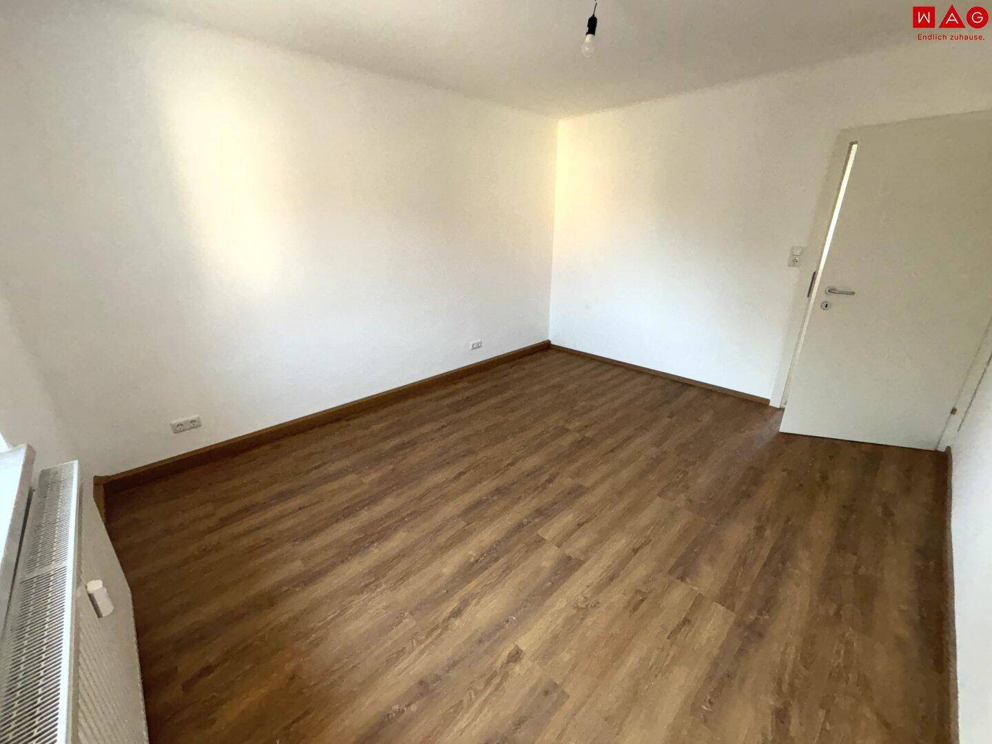 Geräumiges Zimmer mit Laminatboden und Heizkörper, das vielseitige Einrichtungsmöglichkeiten bietet.