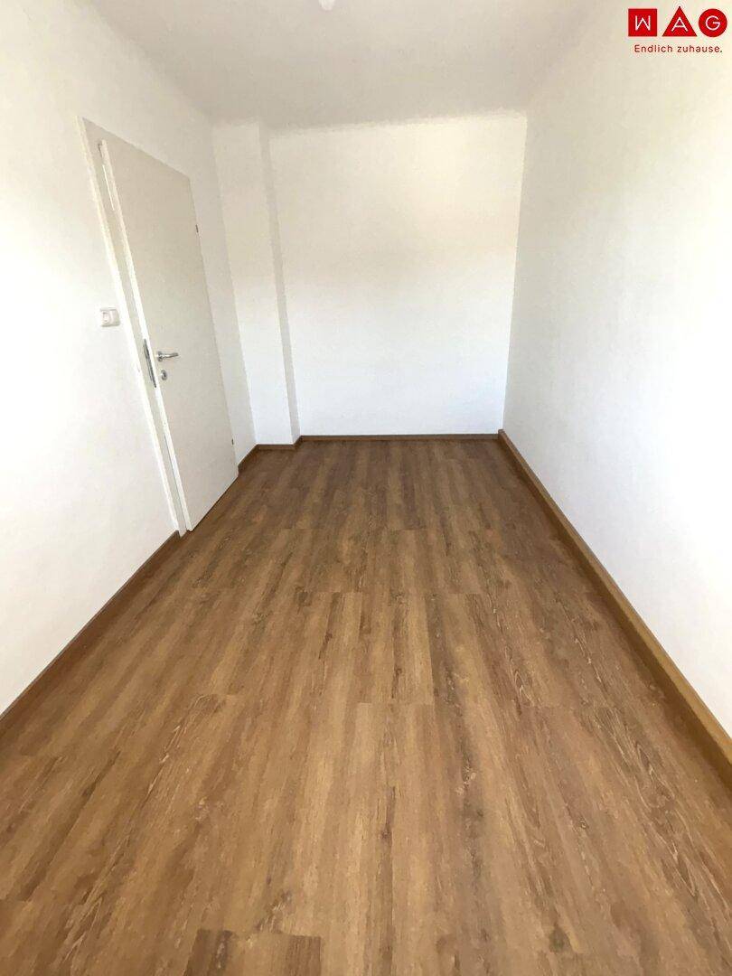 Kleiner, heller Raum mit Laminatboden und weißer Tür, ideal als Abstellraum oder kleines Büro.