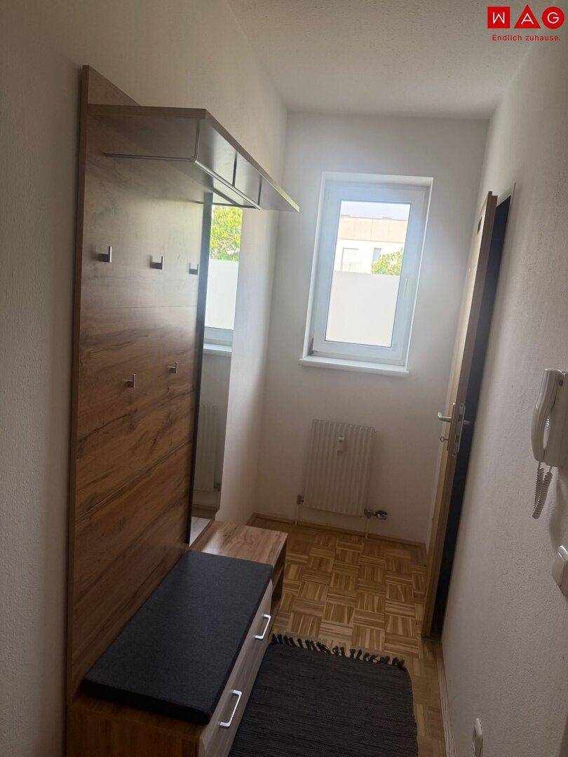 Heller Flur mit Garderobe, Spiegel und Parkettboden, bietet praktischen Stauraum.