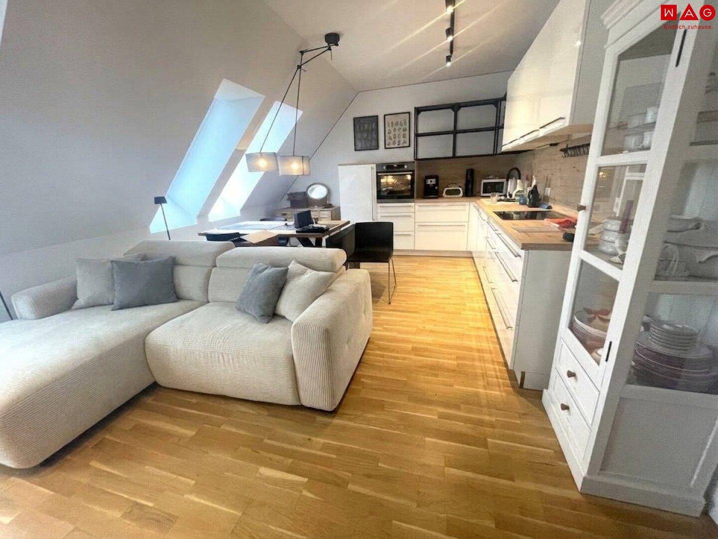 Offener Wohn-Essbereich mit integrierter Küche, modernem Sofa und Dachfenstern für viel Licht.