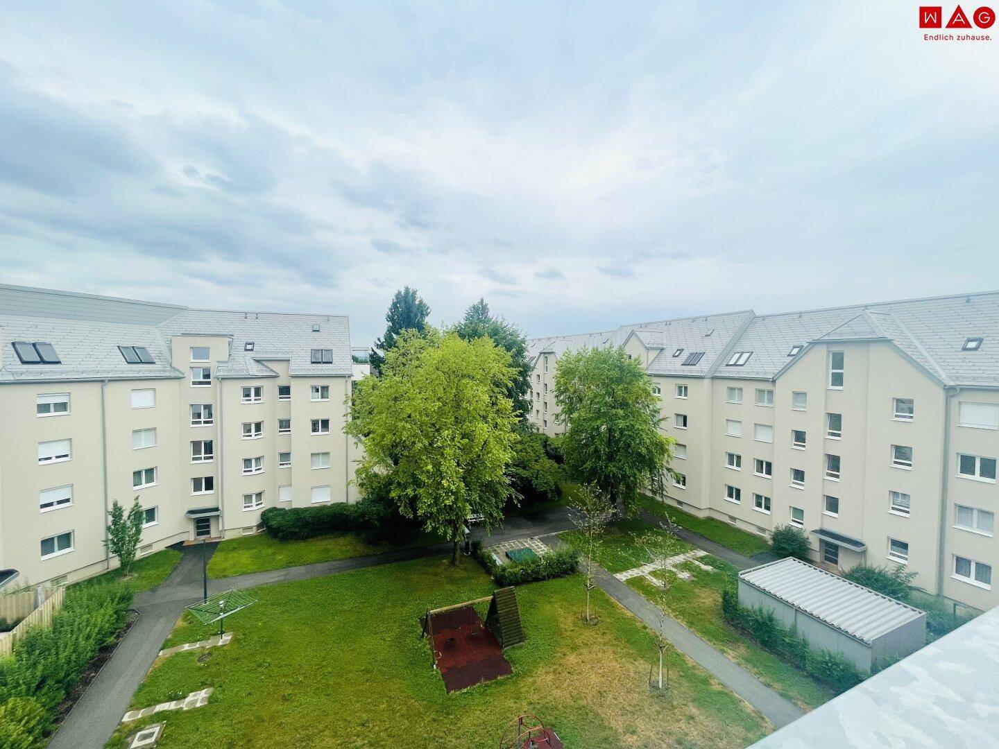 Blick auf eine Wohnanlage mit begrünten Innenhöfen und Spielbereichen zwischen den Gebäuden.