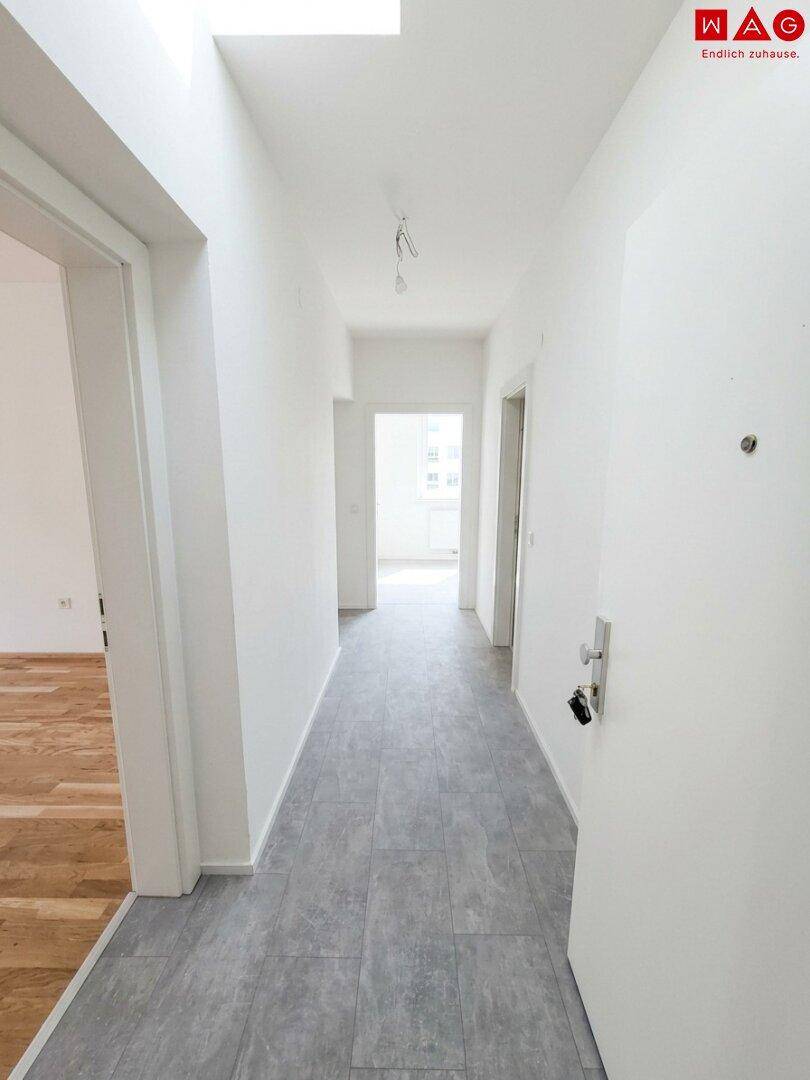 Unmöblierter, heller Flur mit Fliesenboden und weiß gestrichenen Wänden, bereit zum Einzug.