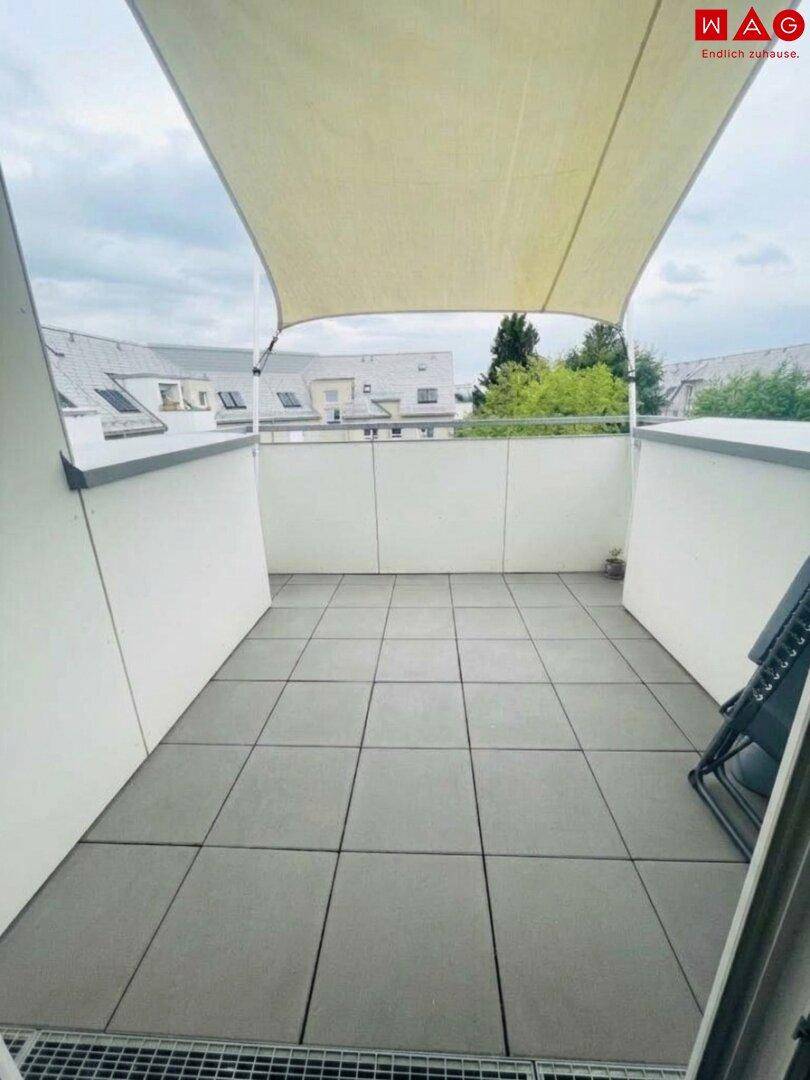 Geräumige Dachterrasse mit Fliesenboden und Sonnenschutz, bietet Platz für Entspannung im Freien.