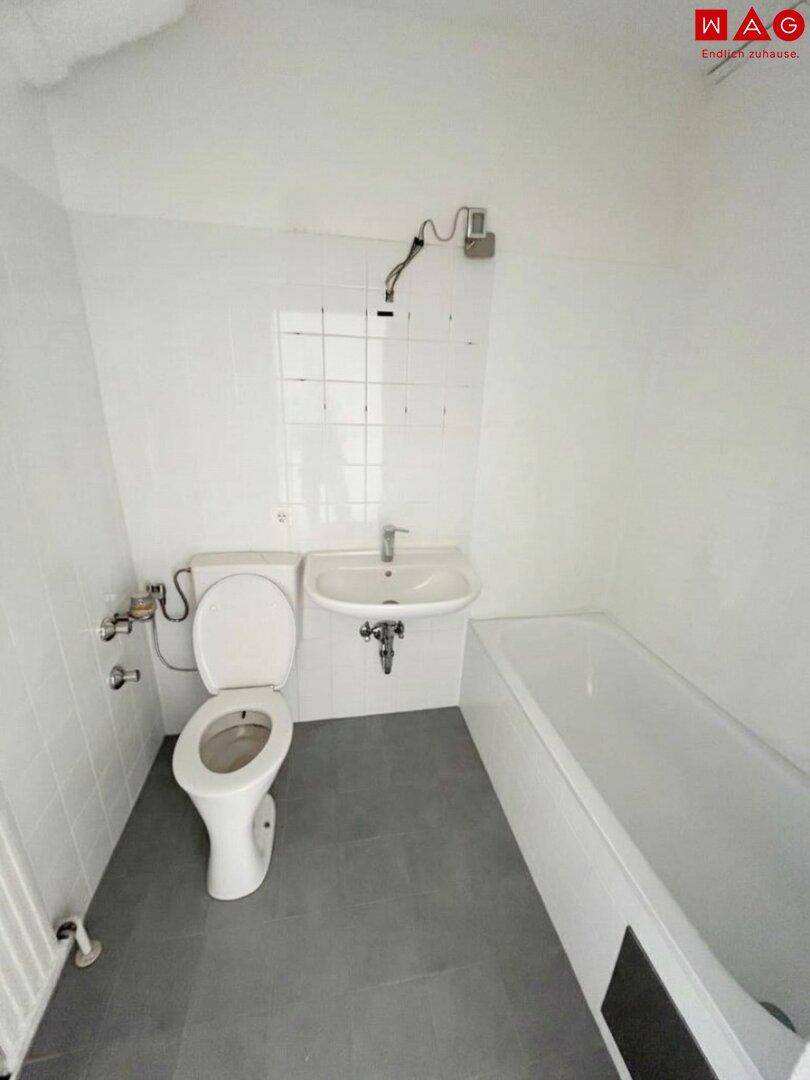 Unmöbliertes Badezimmer mit Badewanne, WC und Waschbecken, bereit für die Einrichtung.