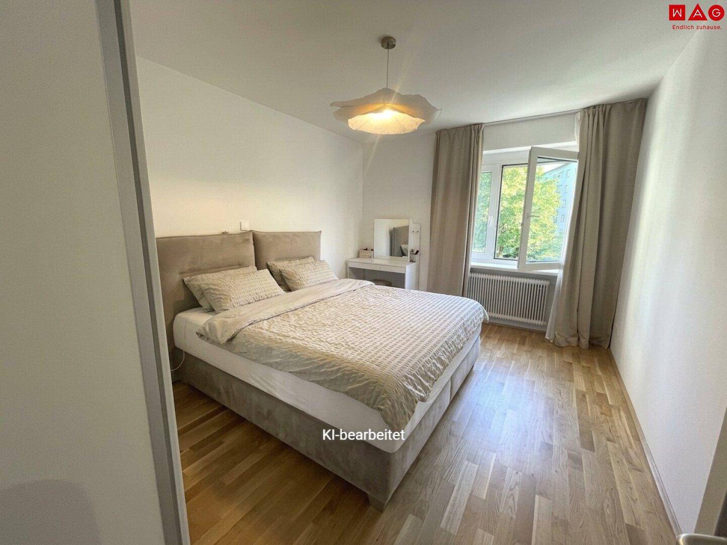 Gemütliches Schlafzimmer mit Doppelbett, Parkettboden und Fenster mit Blick ins Grüne.