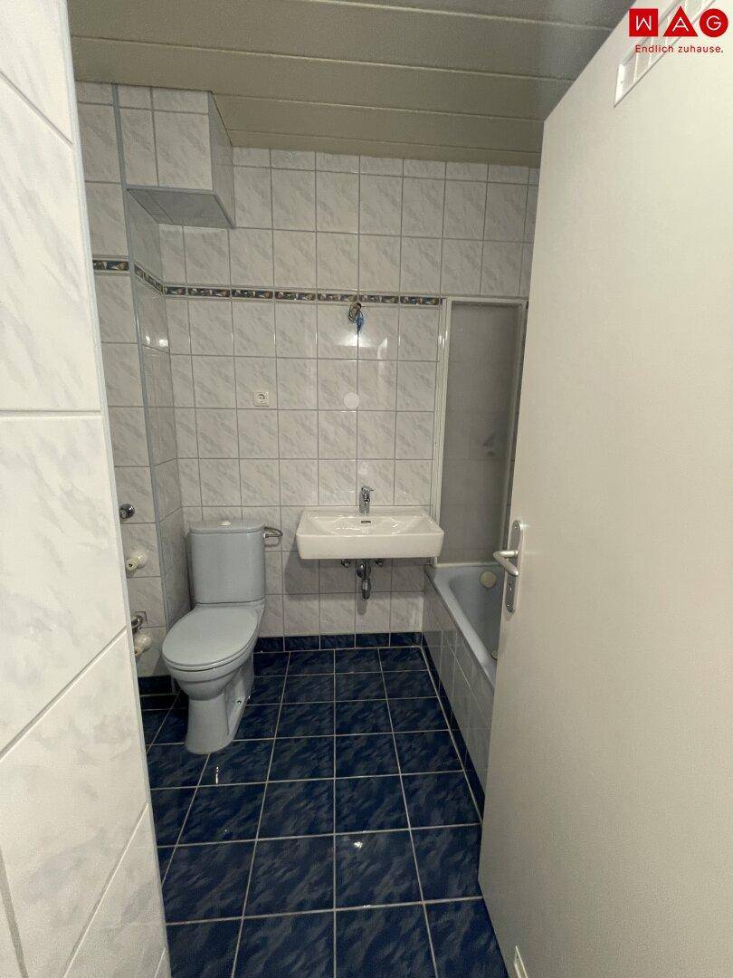 Gefliestes Badezimmer mit Badewanne, WC und Waschbecken in klassischem Design.