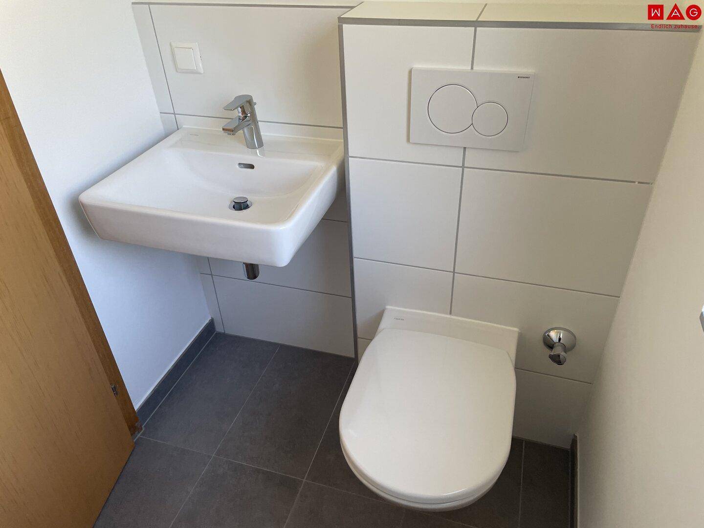 Modernes Gäste-WC mit wandhängender Toilette und kleinem Waschbecken.