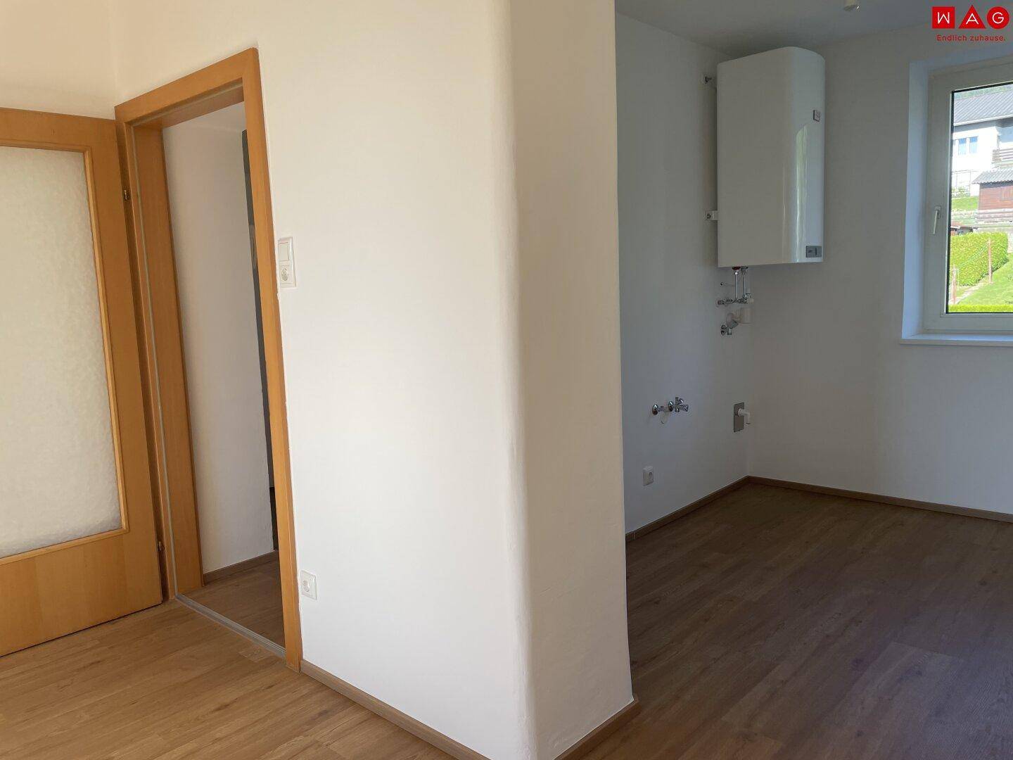 Heller Raum mit Warmwasserboiler und Anschlüssen, geeignet als Hauswirtschaftsraum.