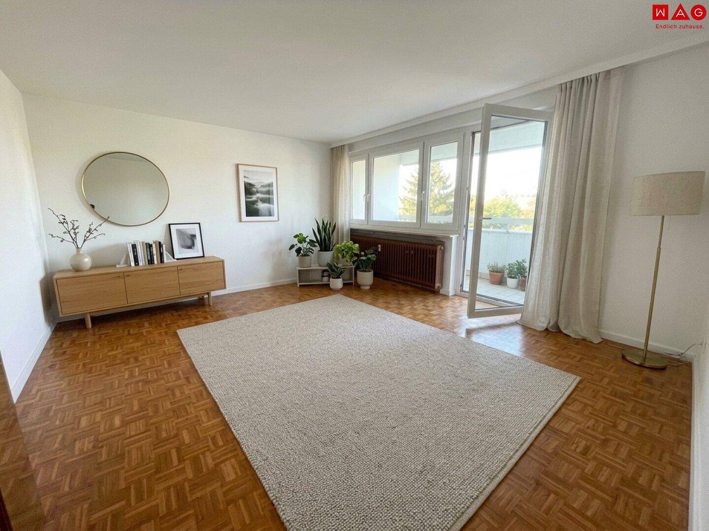 Gemütliches Wohnzimmer mit Parkettboden, Teppich und Zugang zum Balkon.