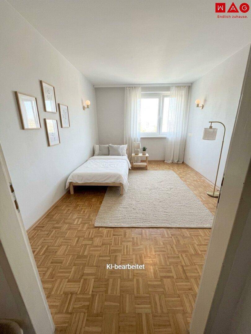 Helles Schlafzimmer mit Parkettboden, Einzelbett und einem großen Fenster.
