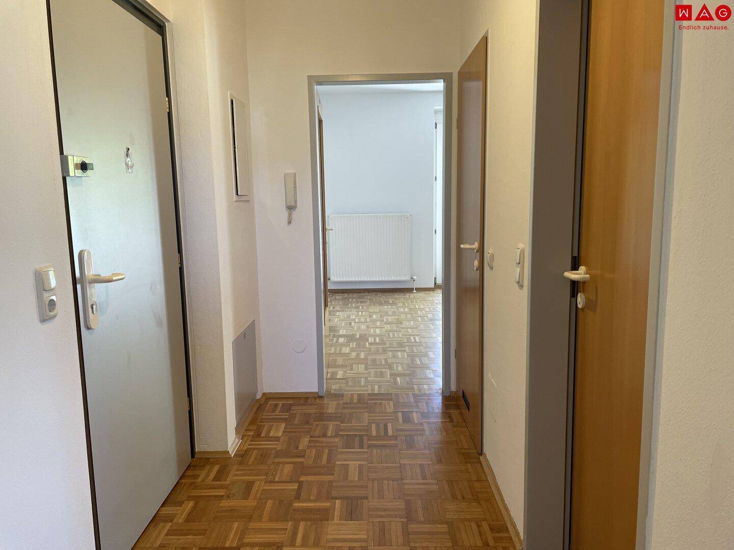 Heller Eingangsbereich mit Parkettboden und Zugang zu den Wohnräumen.