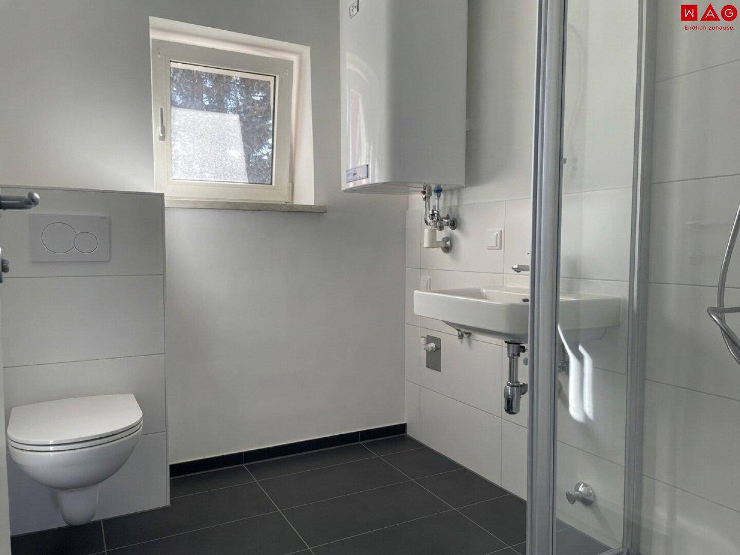Modernes Badezimmer mit Dusche, WC, Waschbecken und Fenster.