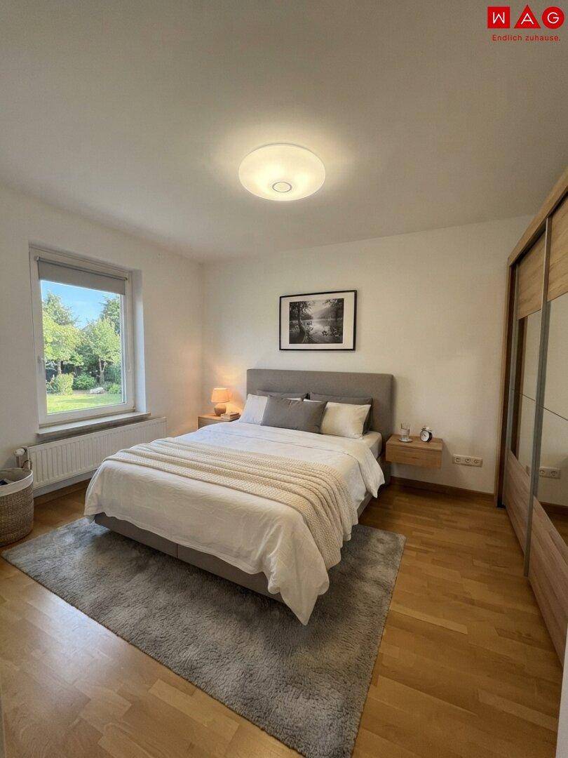 Komfortables Schlafzimmer mit Doppelbett, Holzschrank und Blick ins Grüne.