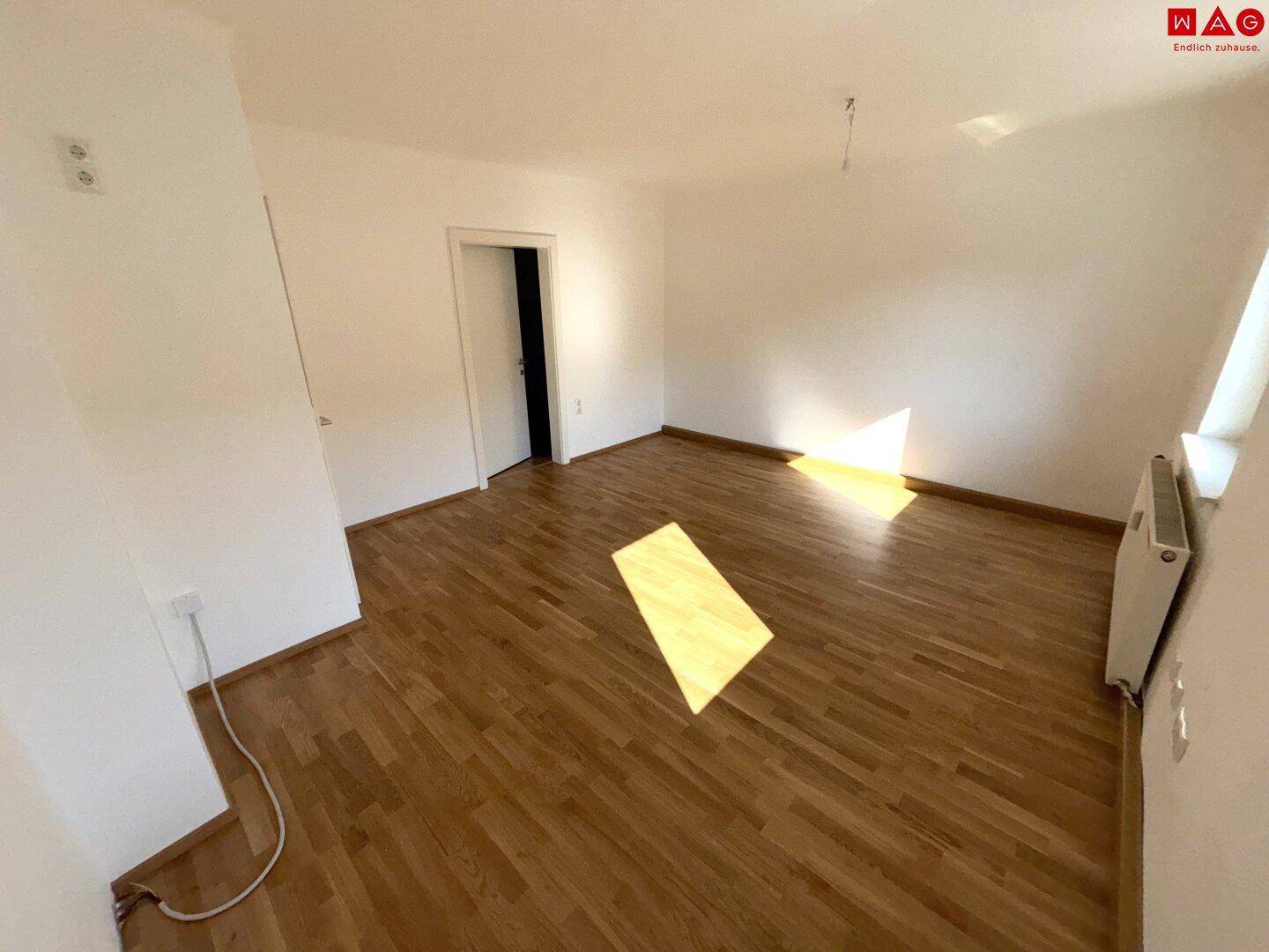 Geräumiges Zimmer mit Holzparkett und viel Tageslicht, ideal für Wohn- oder Schlafbereich.