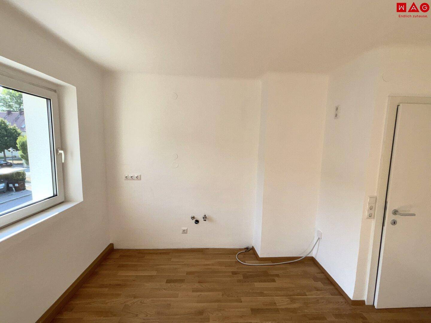 Heller Raum mit Parkettboden und Fenster, vorbereitet für die Installation einer Küche.