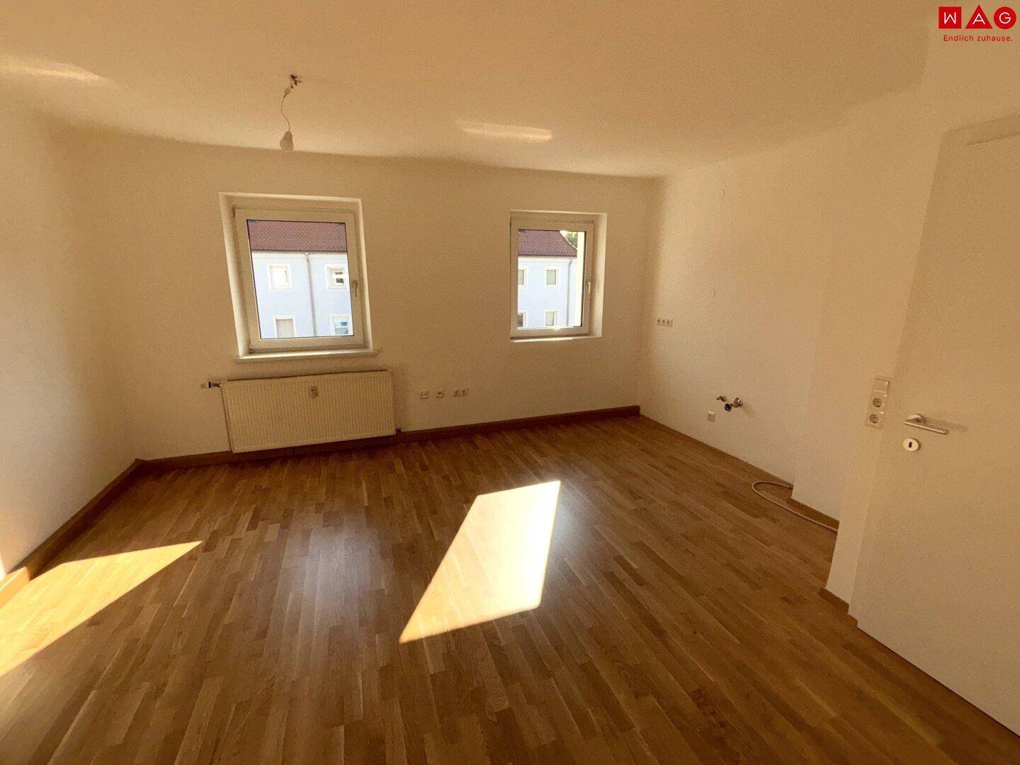 Lichtdurchflutetes Zimmer mit zwei Fenstern und Parkettboden, bietet vielseitige Nutzungsmöglichkeiten.