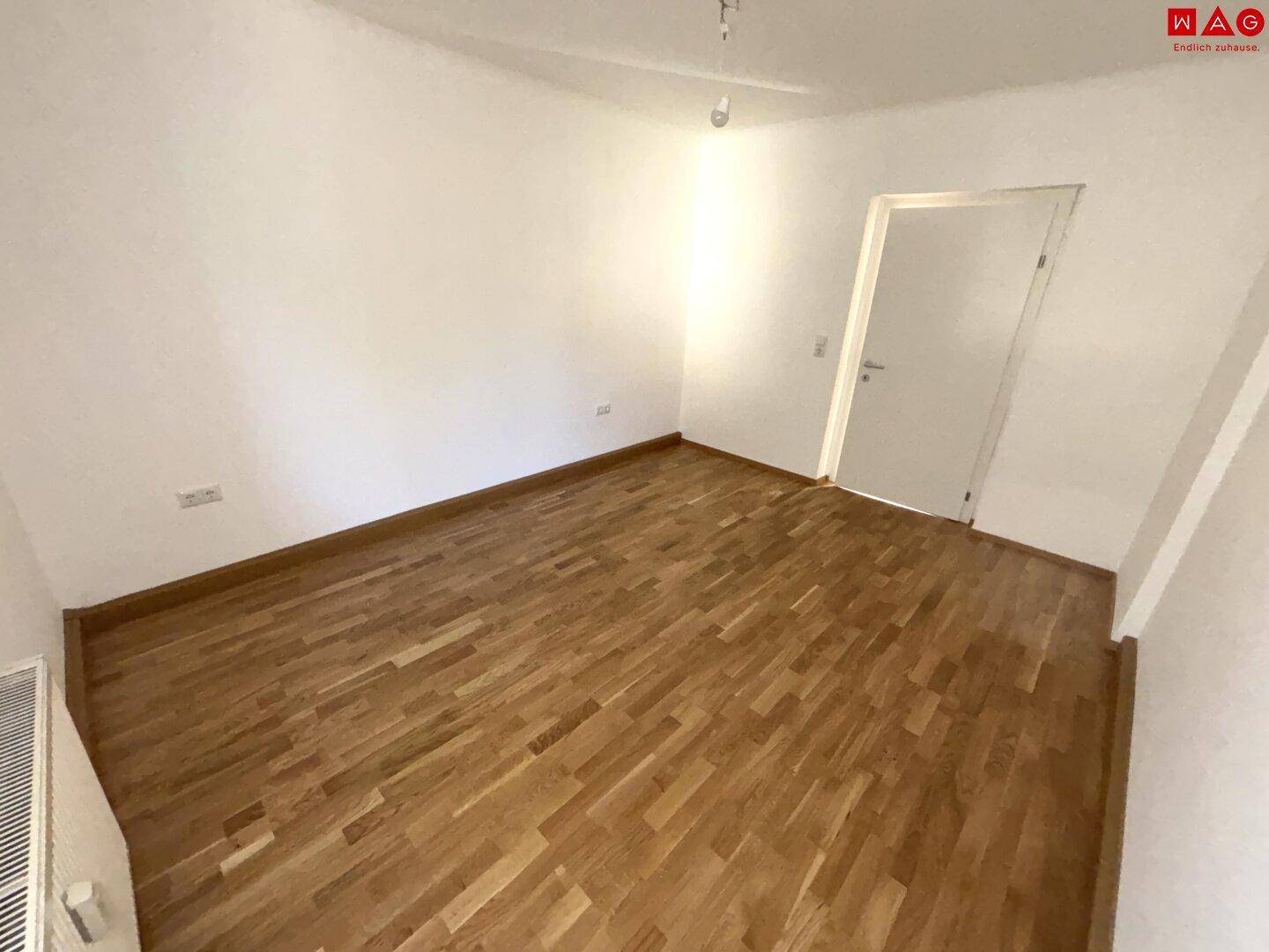 Leeres Zimmer mit Parkettboden und weiß gestrichenen Wänden, bereit für neue Einrichtungsideen.