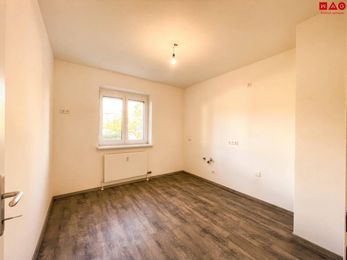 Leerer Raum mit Laminatboden und Fenster, bereit zur individuellen Gestaltung.
