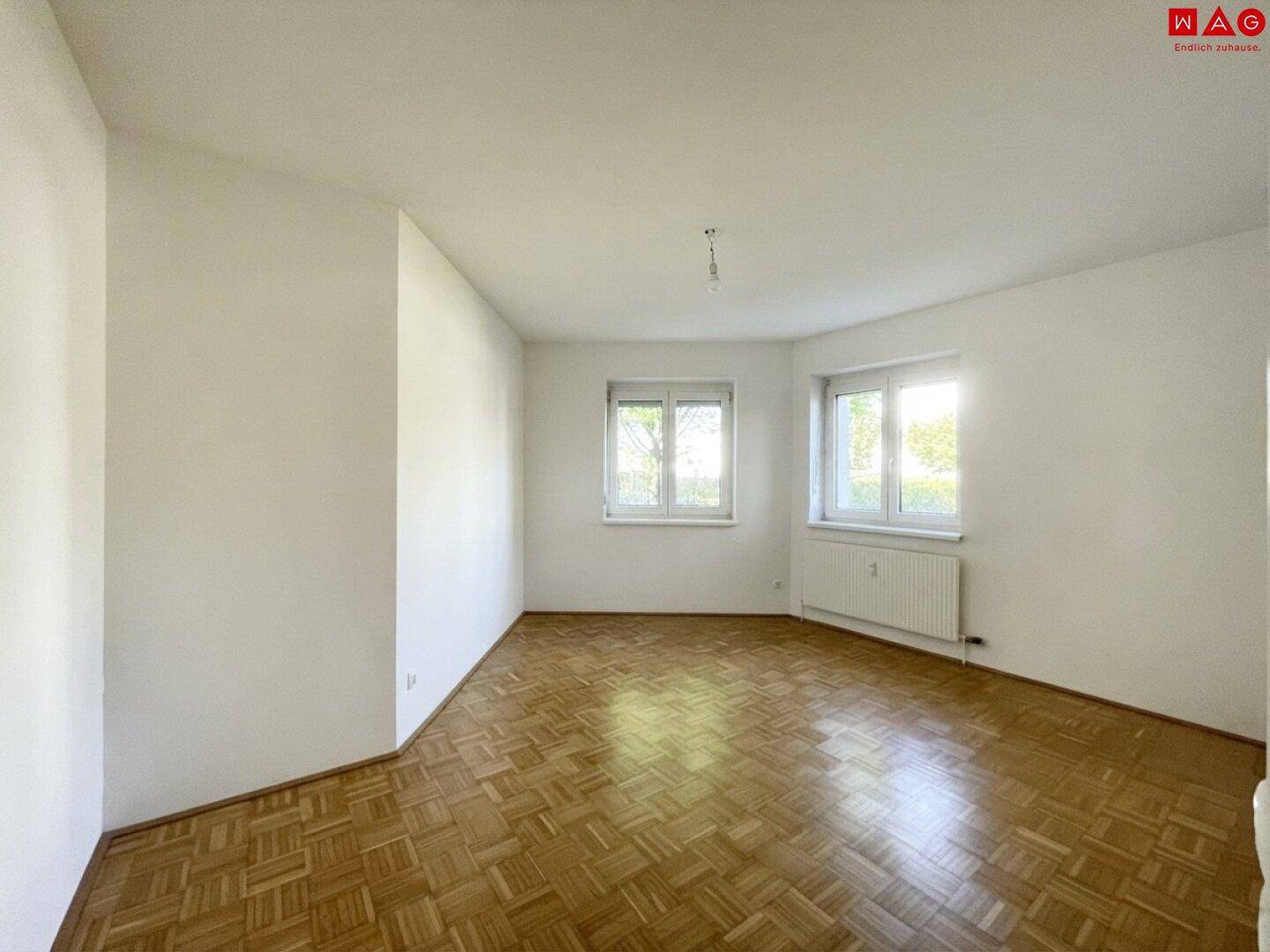 Heller Raum mit Parkettboden und mehreren Fenstern, ideal als Kinderzimmer.
