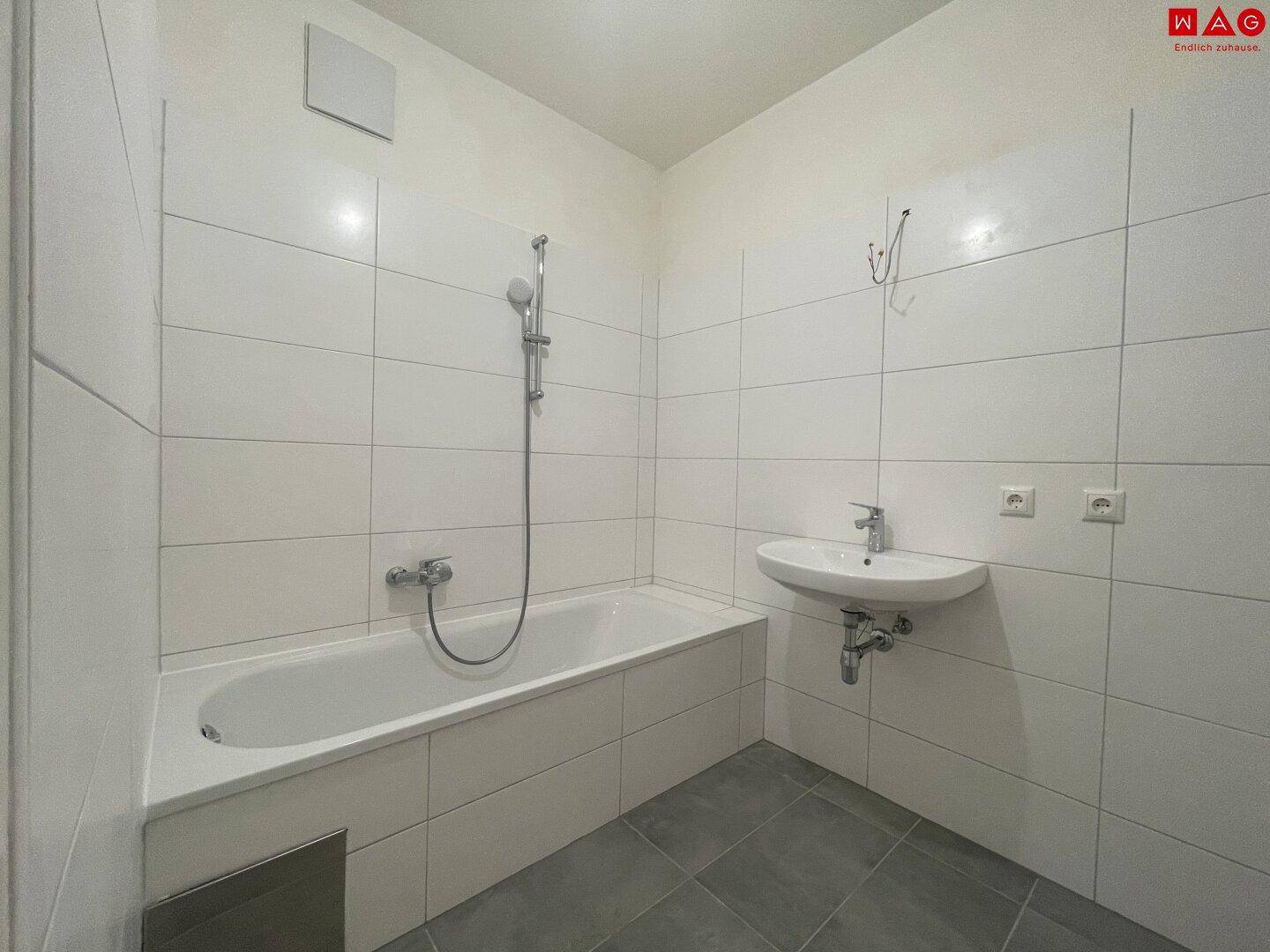 Helles Badezimmer mit Badewanne und Waschbecken, bereit zur individuellen Einrichtung.