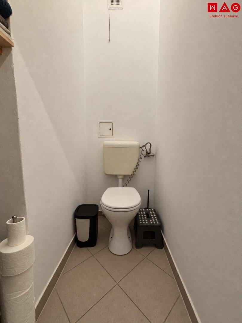 Separates WC mit Toilette und Fliesenboden, ideal für Gäste.