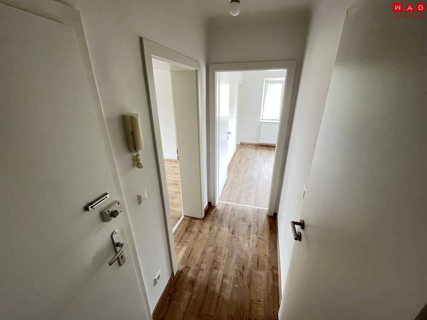 Heller Flur mit Laminatboden und weißen Türen, der zu weiteren Zimmern der Wohnung führt.