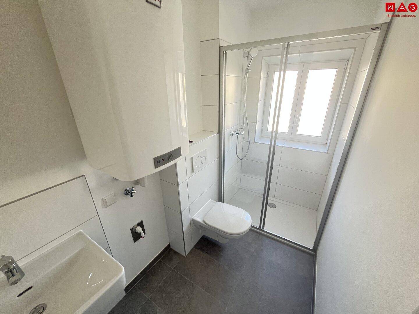Modernes Badezimmer mit Duschkabine, wandhängendem WC, Waschbecken und einem Fenster für Tageslicht.