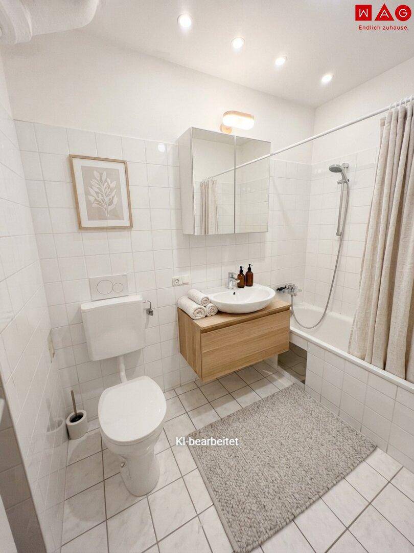 Helles Badezimmer mit Badewanne, WC, Waschbecken und Spiegelschrank, weiß gefliest.