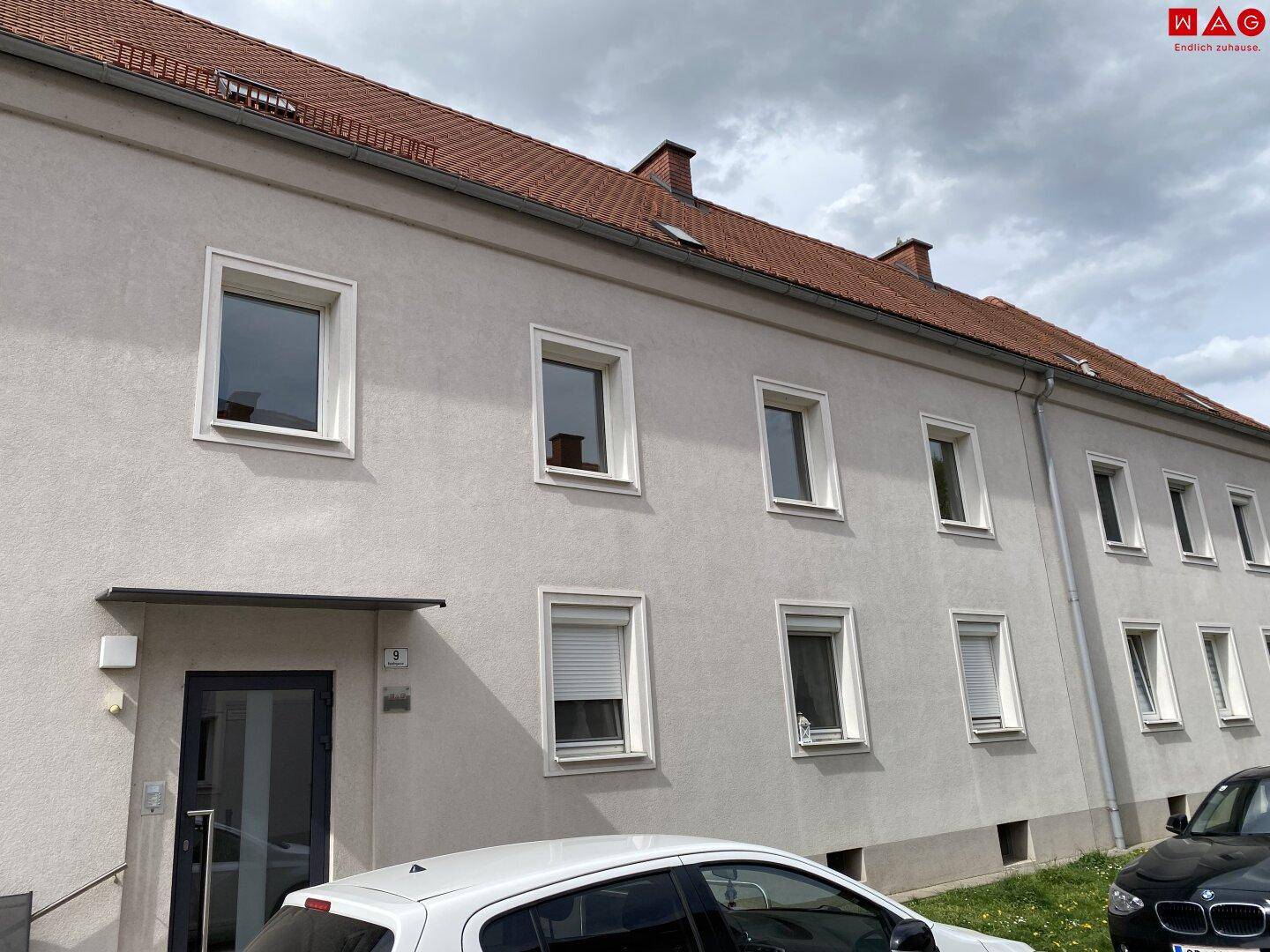 Fassade eines Mehrfamilienhauses mit mehreren Fenstern und einem modernen Eingangsbereich.