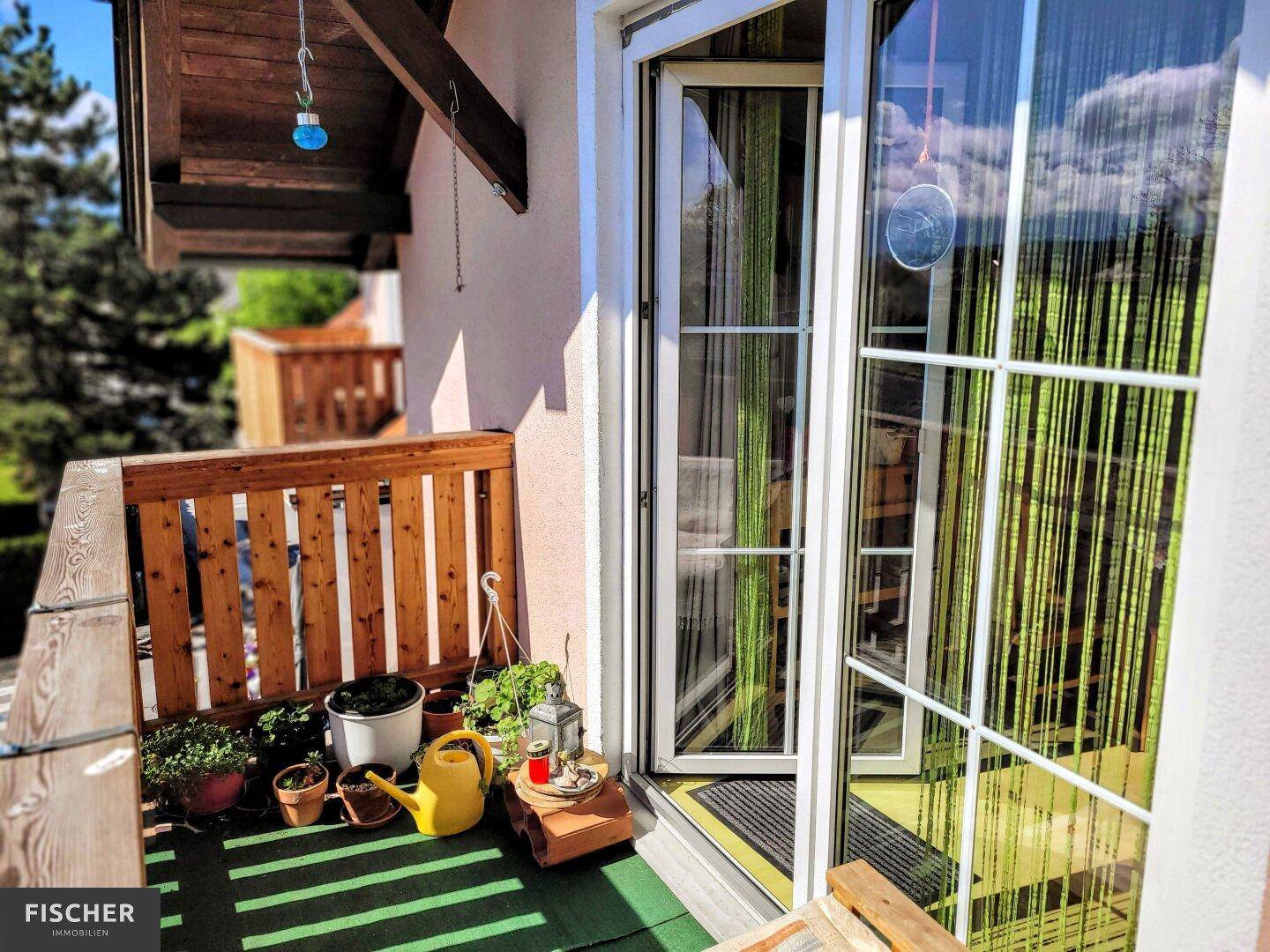 Balkonzugang vom Innenraum mit Blick auf das Holzgeländer und die Umgebung.