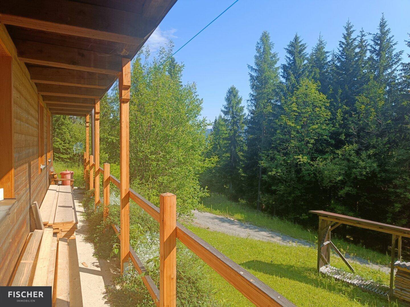 Langer Holzbalkon mit Geländer und weitem Blick auf die umliegende Waldlandschaft.