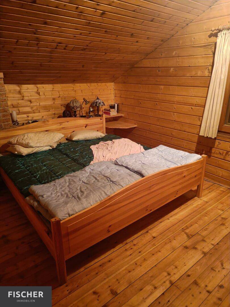 Schlafzimmer mit Doppelbett, komplett in Holz gehalten und Dachschrägen für gemütliche Atmosphäre.
