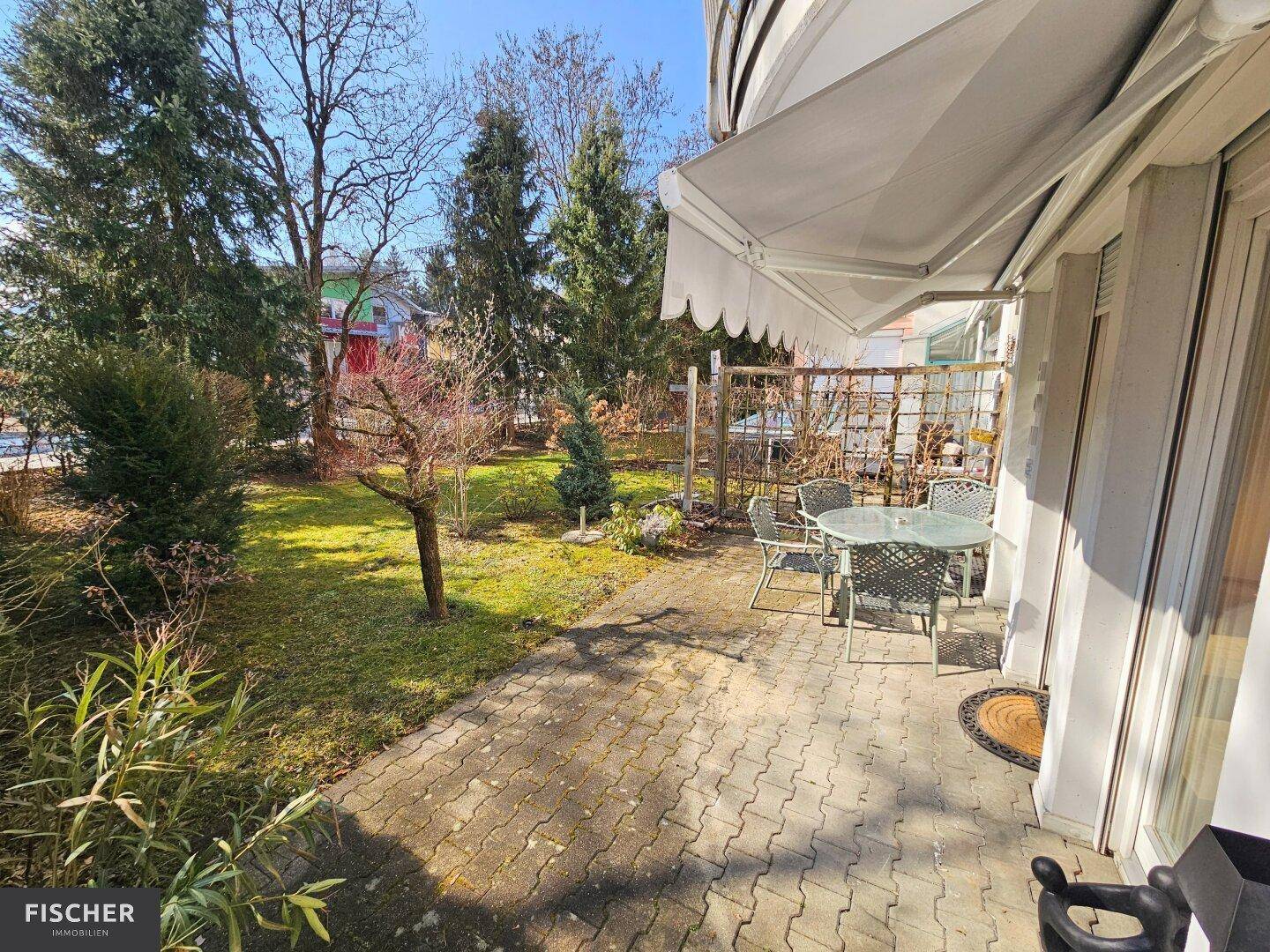 Sonniger Terrassenbereich mit Gartenmöbeln und Zugang zum grünen, gepflegten Garten.