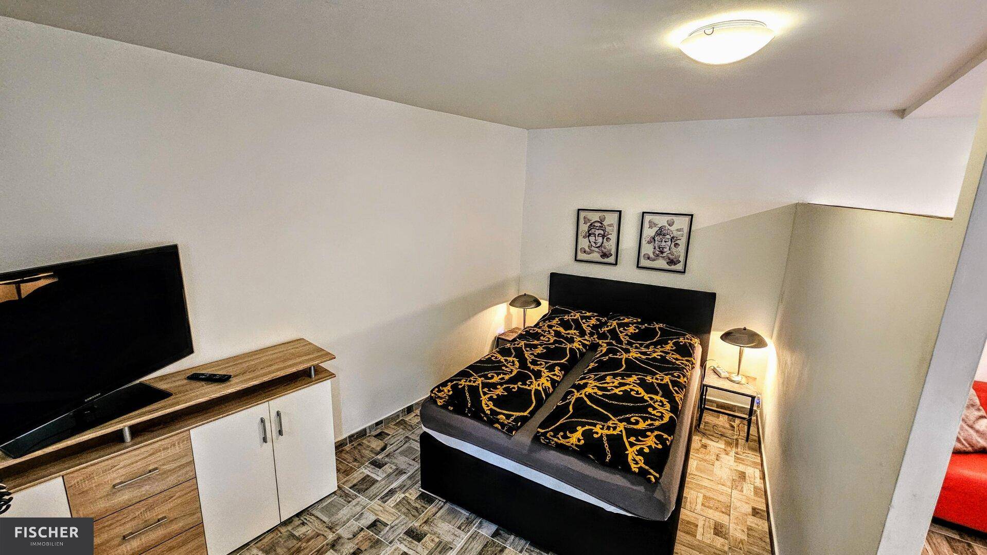 Gemütlicher Schlafbereich mit Doppelbett, Nachttischen und Fernseher auf einem Sideboard.