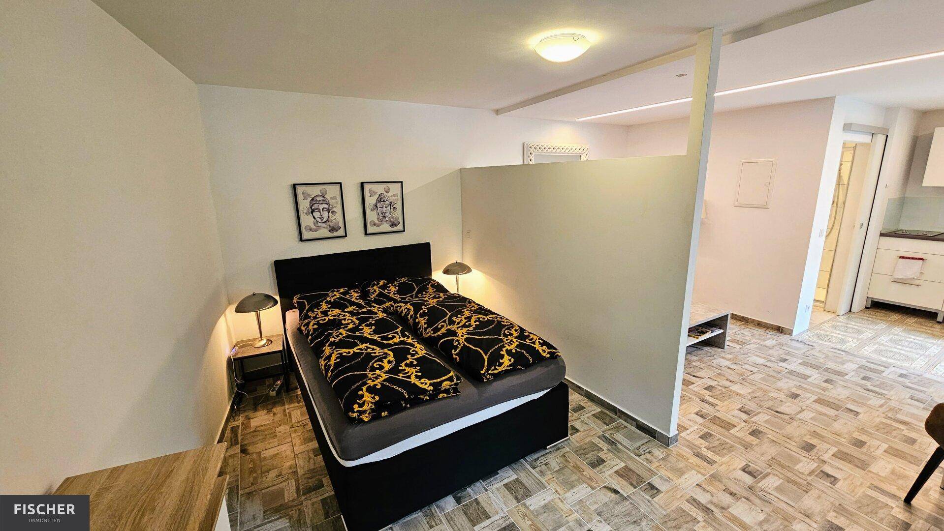 Schlafbereich mit Doppelbett und Nachttischen, durch eine Trennwand vom Wohnbereich abgeteilt.