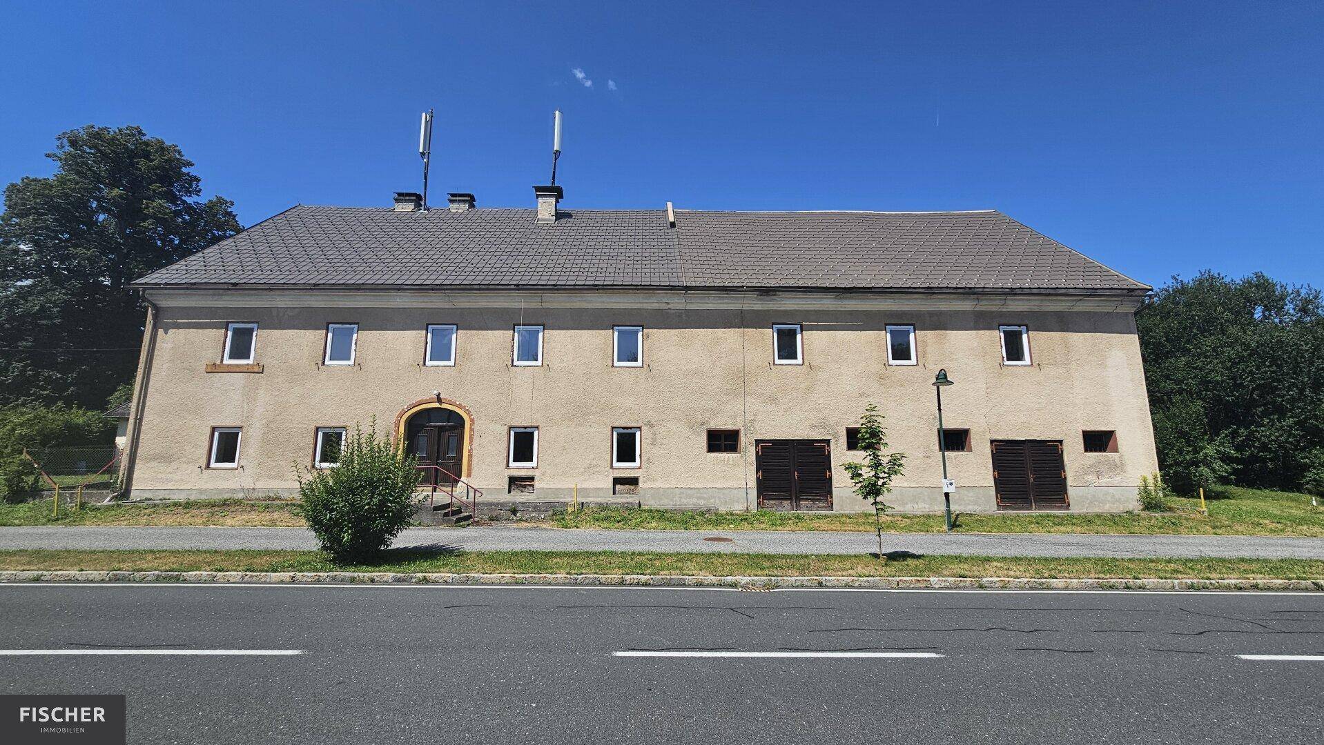 Altes, großes Gebäude mit mehreren Fenstern und Garagentoren an einer Straße gelegen.