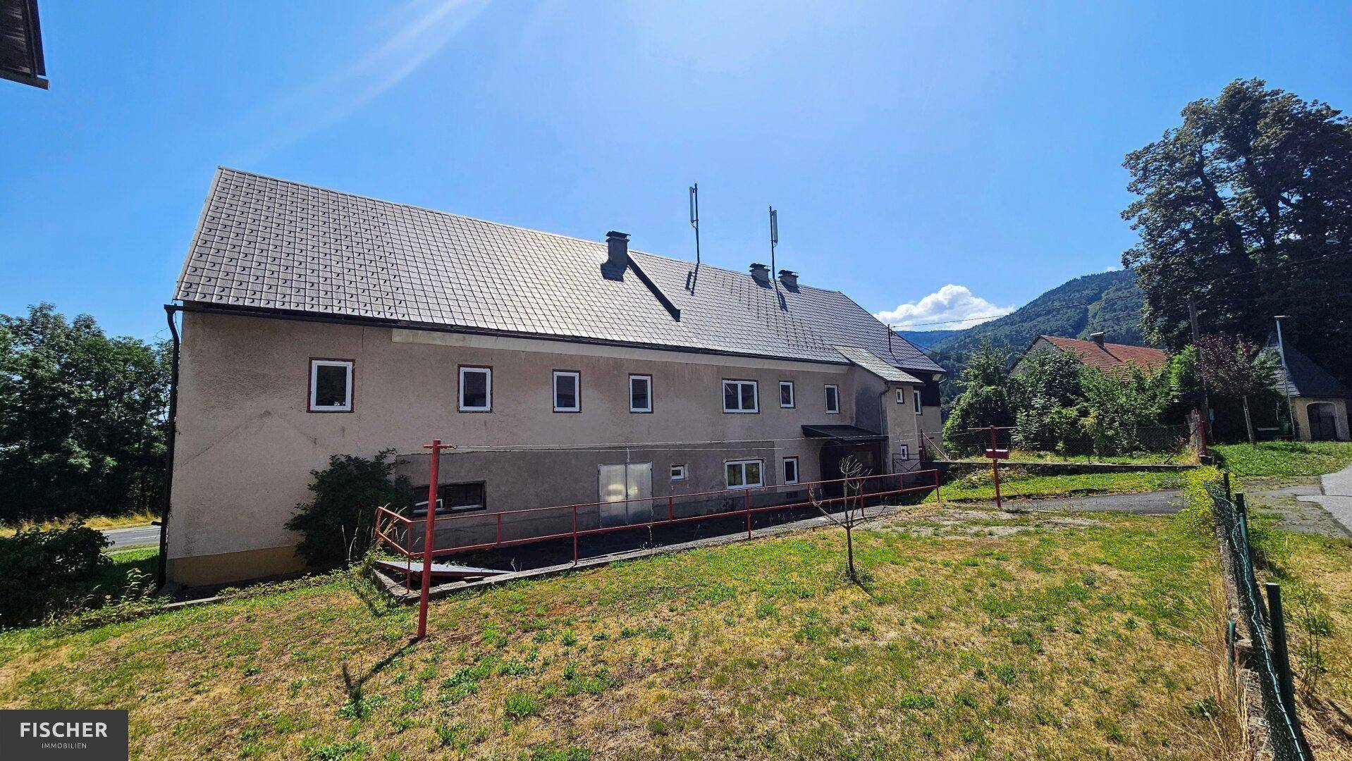 Seitenansicht des alten Gebäudes mit Gartenbereich und Blick auf die umliegende Landschaft.