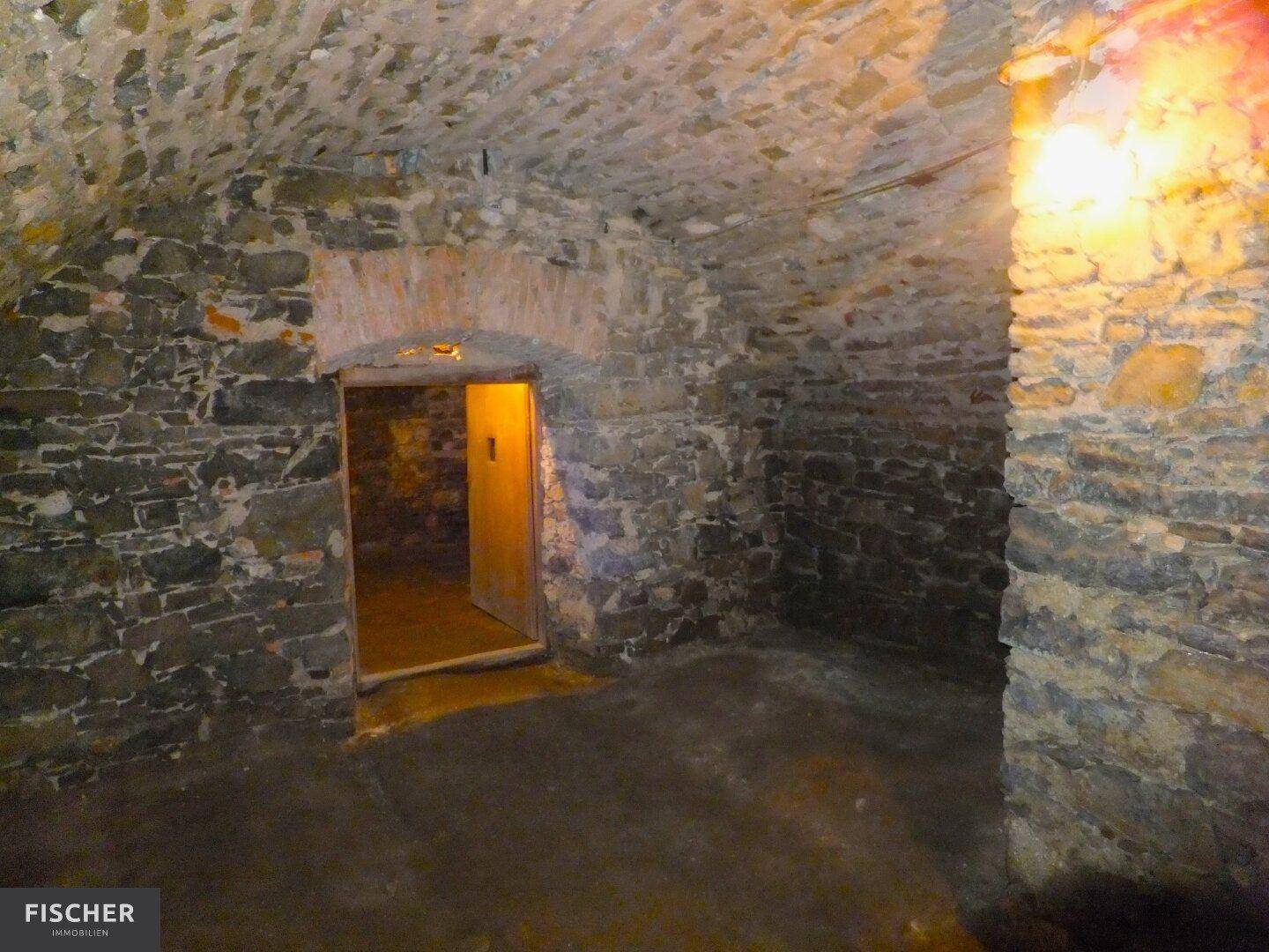 Historischer Weinkeller mit robusten Steinmauern und gewölbter Decke, der eine einzigartige Atmosphäre bietet.